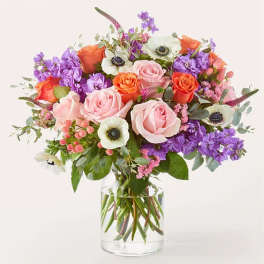 Bouquet of pink, orange, and purple flowers in a clear glass vase