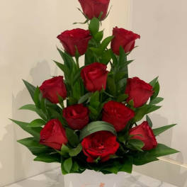 Red roses arranged in a white box with green leaves