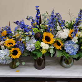 Blue and yellow floral arrangements in glass vases