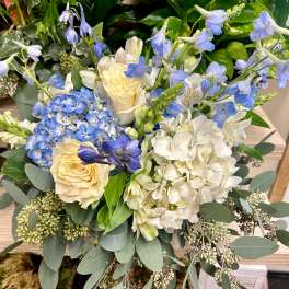 Blue and white floral arrangement with roses, hydrangeas, and delphinium