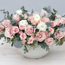Low white bowl arrangement of blush pink roses and white ranunculus