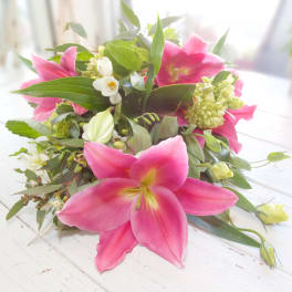 Pink lilies and white flowers arranged low on a table