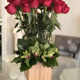 Tall arrangement of red roses with green orchids in a wooden box