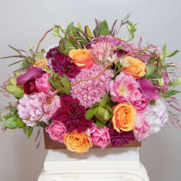 Pink and orange floral arrangement in a rectangular container
