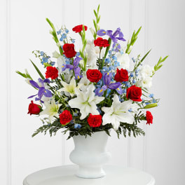 Red, white, and purple flowers arranged in a white vase