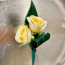 Two pale yellow roses with dark green leaves on a teal stem wrap