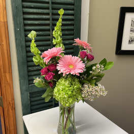 Pink gerbera daisies and roses in a clear glass vase