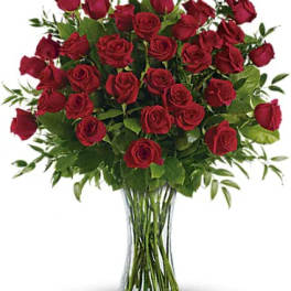 Tall arrangement of red roses in a clear glass vase