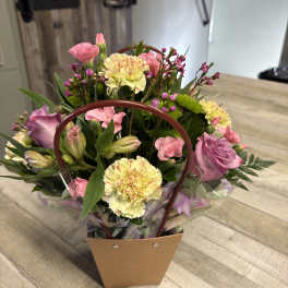Mixed pink and yellow bouquet in a handled gift bag