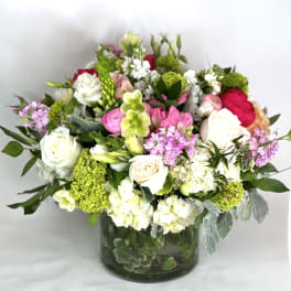 Mixed bouquet of white, pink, and green flowers in a glass vase