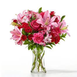 Pink lilies and red roses arranged in a clear glass vase