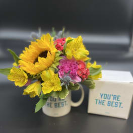 Bright mixed bouquet in a mug beside a matching gift box