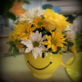 Yellow smiley-face mug filled with yellow and white daisies