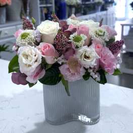 Pink and white rose bouquet in a ribbed glass vase