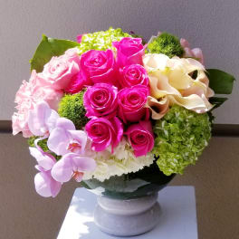 Pink roses and orchids arranged in a round vase centerpiece