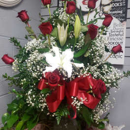 Red roses and white lilies in a glass vase with a red ribbon