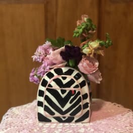 Small pink and purple flower arrangement in a black-and-white patterned vase
