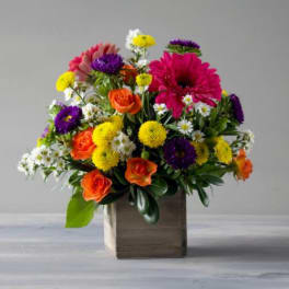 Mixed bouquet of orange roses, pink gerberas, and yellow and purple mums in a wooden box