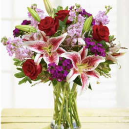 Bouquet of red roses and pink lilies in a clear glass vase