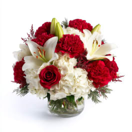 Red and white bouquet with lilies, roses, carnations, and hydrangeas in a glass vase