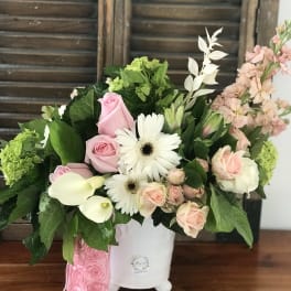 Pink roses and white daisies arranged in a white vase