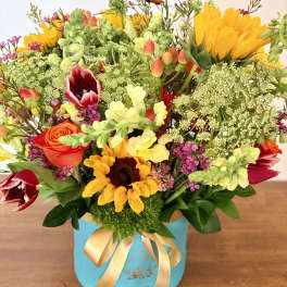Colorful mixed bouquet in a blue hatbox with a gold ribbon