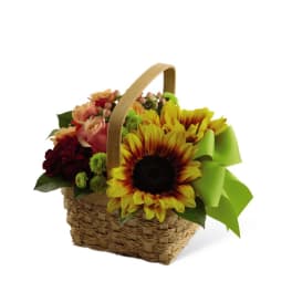 Basket arrangement with sunflowers, roses, and a bright green bow