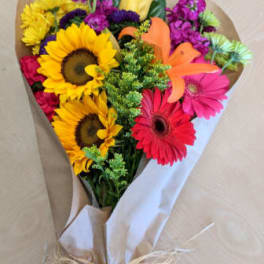 Bouquet of sunflowers, gerbera daisies, and mixed blooms wrapped in paper