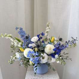 Blue and white floral arrangement in a light blue vase