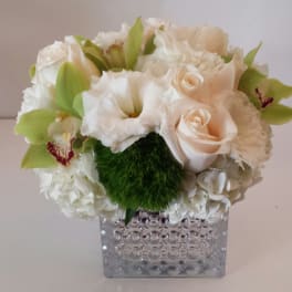 White and pale peach floral arrangement in a clear textured vase