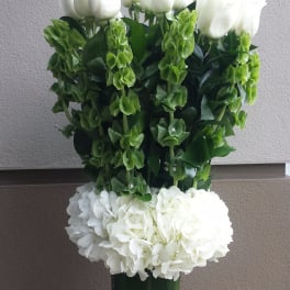 White roses and hydrangeas in a tall green vase