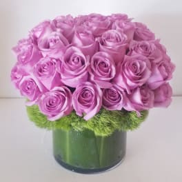 Pink rose bouquet in a green glass vase with a mossy base