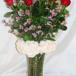 Bouquet of red roses and pale pink flowers in a tall glass vase