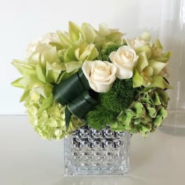Green and cream floral arrangement in a clear textured vase