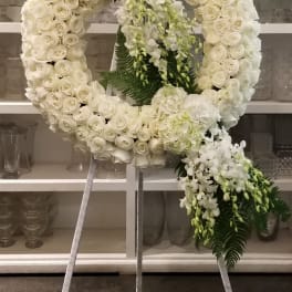 Large white floral wreath on a stand with cascading orchids