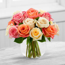 Bouquet of pink, peach, and cream roses in a clear glass vase