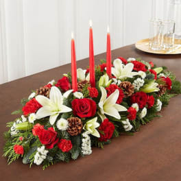 Holiday centerpiece with red candles, white lilies, and red roses