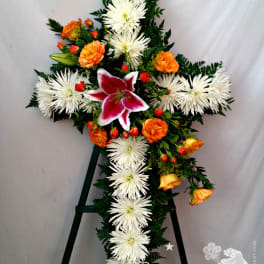 Cross-shaped floral spray with white spider mums, orange roses, and a pink lily