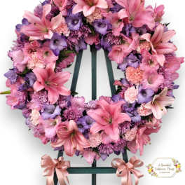 Pink and purple floral wreath on a standing easel with ribbon bows