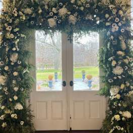 Large floral arch of white blooms framing double doors