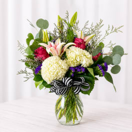 Bouquet of white hydrangeas, pink lilies, and roses in a glass vase