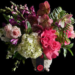 Mixed bouquet of pink roses, hydrangeas, and hellebores in a decorative vase