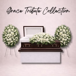 White funeral casket with white floral sprays and standing wreaths