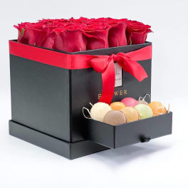 Red roses in a black gift box with a drawer of macarons