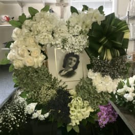 Large white funeral wreath with a framed portrait in the center