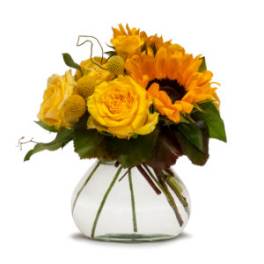 Yellow roses and sunflowers arranged in a clear glass vase.