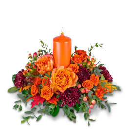 Orange candle surrounded by orange and burgundy flowers
