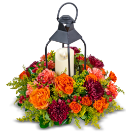 Lantern with a candle surrounded by orange and burgundy flowers