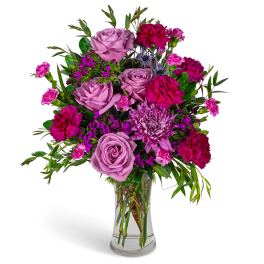 Lavender roses and magenta flowers arranged in a clear glass vase