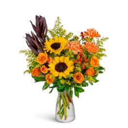 Bouquet of sunflowers, orange roses, and carnations in a clear glass vase